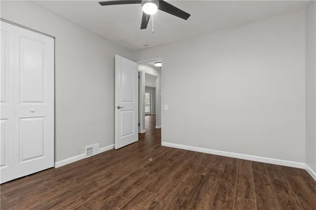an empty room with wooden floor ceiling fan and window