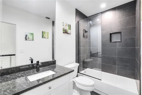 a bathroom with a granite countertop sink toilet and shower