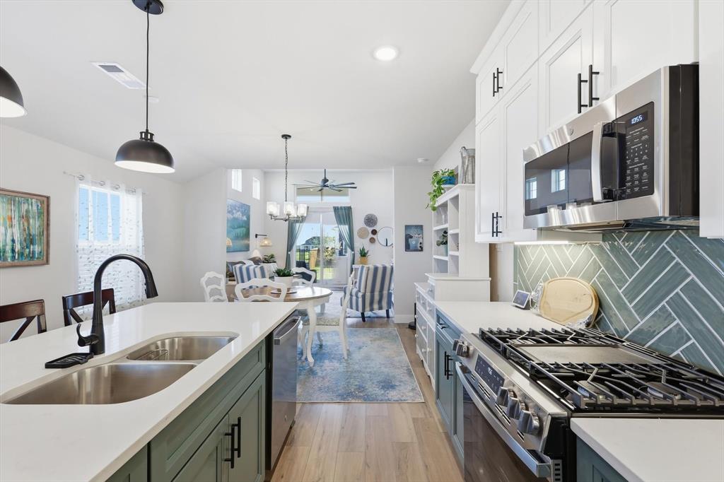 1018 Abigail Way Midlothian, TX 76065 - Photo 13 of 26 a kitchen with stainless steel appliances granite countertop a stove a sink dishwasher and white cabinets with wooden floor