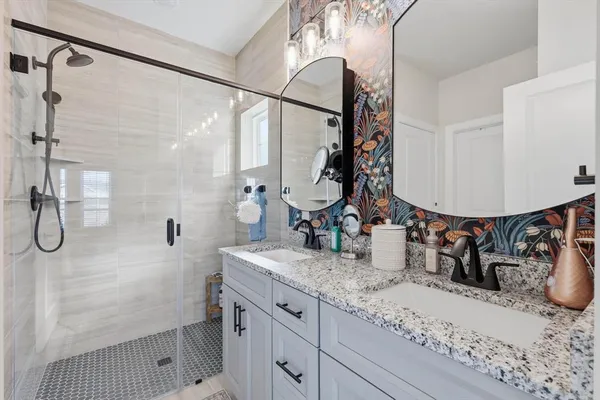 a bathroom with a granite countertop sink a mirror and shower