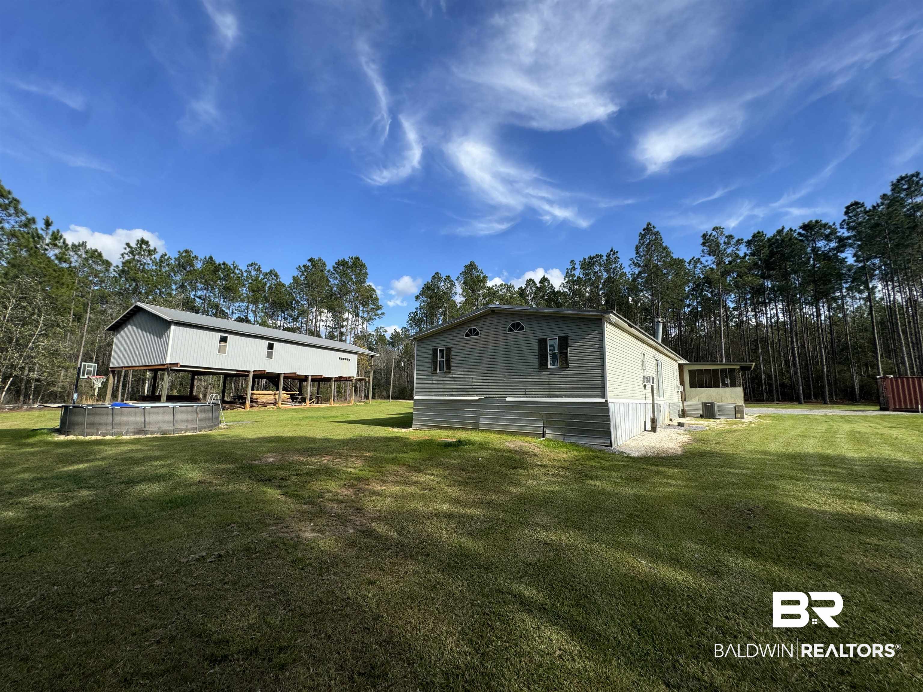 51235 Phillipsville Road Bay Minette, AL 36507 - Photo 5 of 63 Back of property with an outdoor pool, a lawn, view of wooded area, and a sunroom