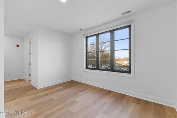 an empty room with wooden floor and windows