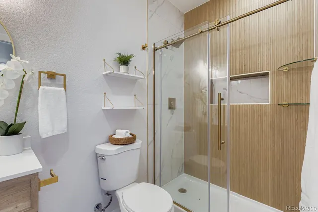 a bathroom with a granite countertop sink a toilet and shower