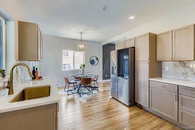 a kitchen with stainless steel appliances granite countertop a refrigerator a sink a stove and white cabinets with wooden floor