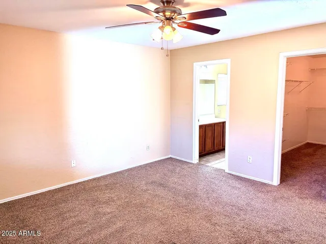 an empty room with chandelier fan and windows