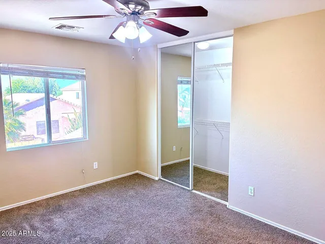 an empty room with windows and fan