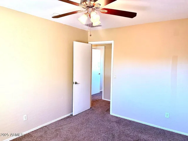 an empty room with a ceiling fan and a window