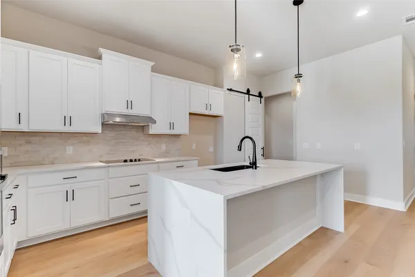 a kitchen with stainless steel appliances granite countertop a sink a stove a refrigerator and white cabinets with wooden floor