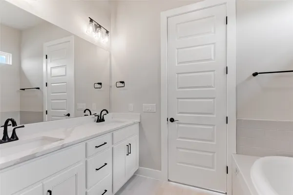 a bathroom with a double vanity sink a mirror and a bathtub