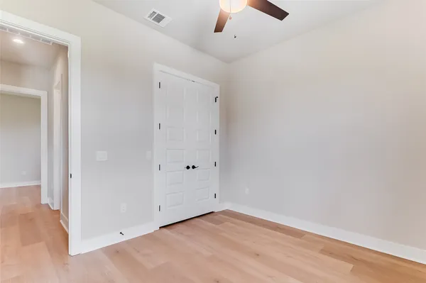 an empty room with a ceiling fan and wooden floor