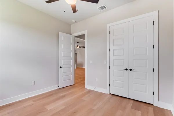 an empty room with wooden floor cabinet and windows