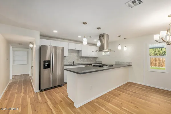 a kitchen with stainless steel appliances granite countertop a refrigerator a stove and a wooden floors