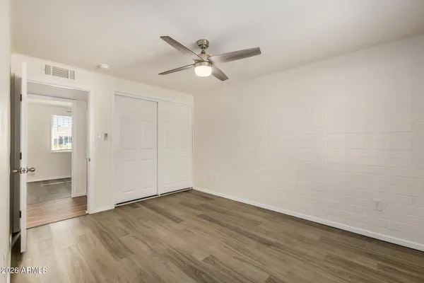 an empty room with wooden floor ceiling fan and windows