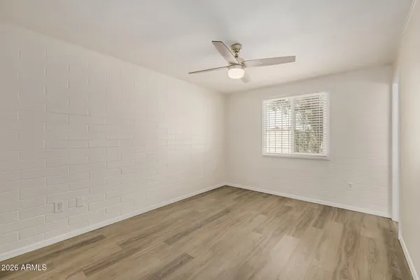 an empty room with wooden floor fan and windows