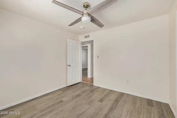 an empty room with wooden floor ceiling fan and a ceiling fan