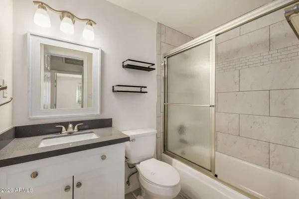 a bathroom with a granite countertop sink toilet a mirror and shower
