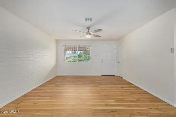 an empty room with windows and ceiling fan