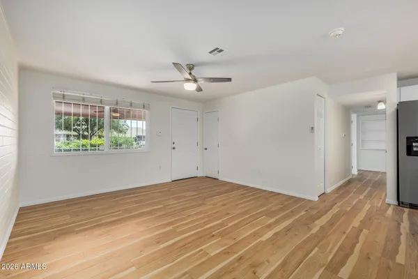 a view of empty room with wooden floor and fan