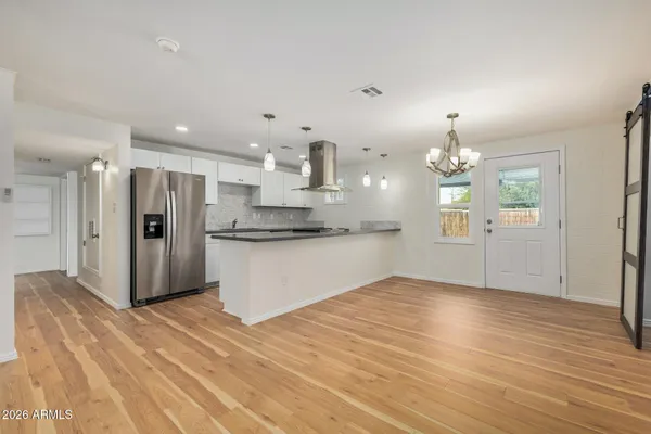 a view of a kitchen with refrigerator and wooden floor