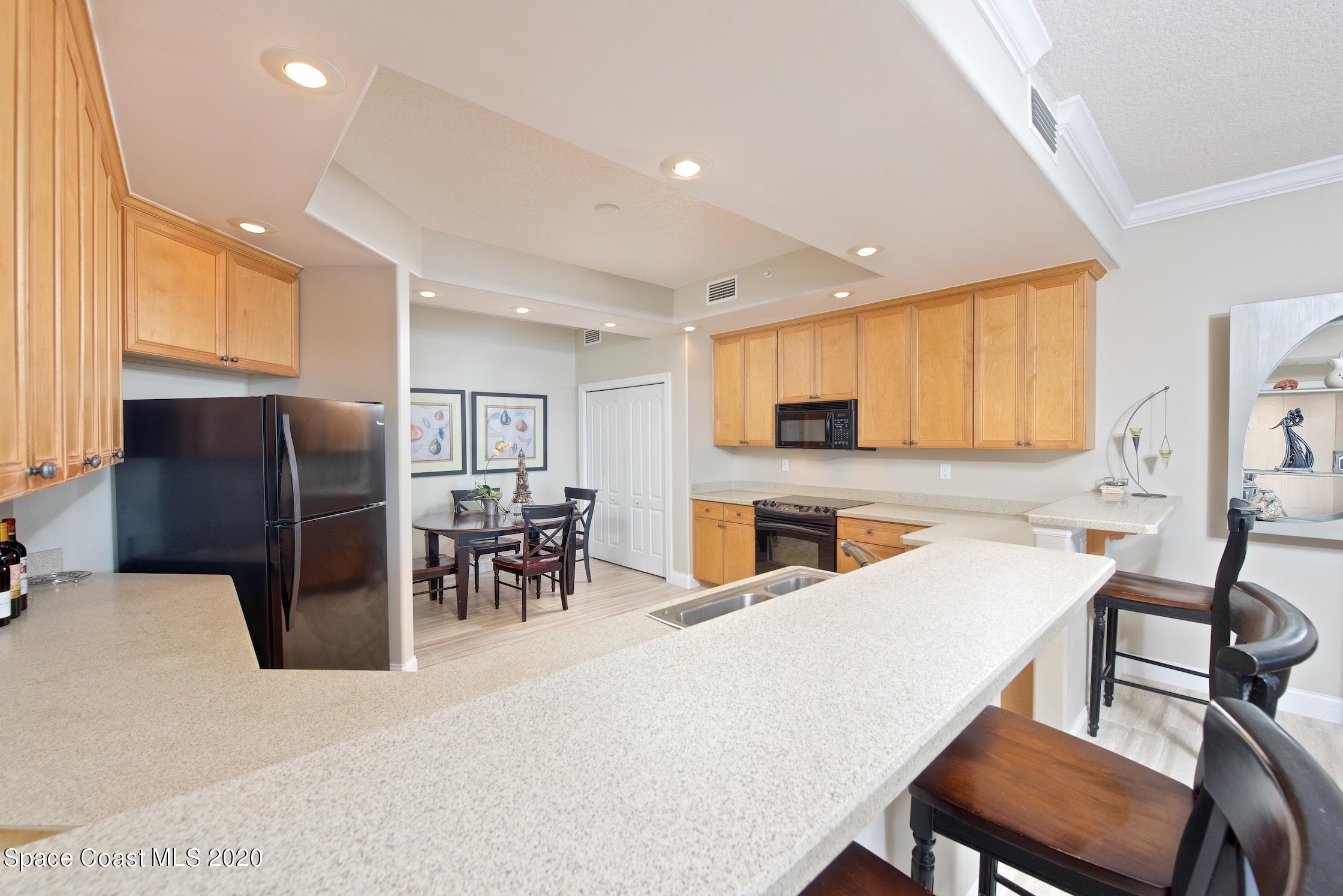 4955 Dixie Highway Northeast, Unit 404 Palm Bay, FL 32905 - Photo 14 of 50 a kitchen with stainless steel appliances granite countertop a refrigerator a stove a sink a dining table and chairs with wooden floor