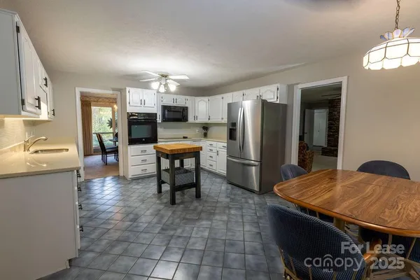 a kitchen with stainless steel appliances kitchen island granite countertop a refrigerator a stove a sink a dining table and chairs with wooden floor