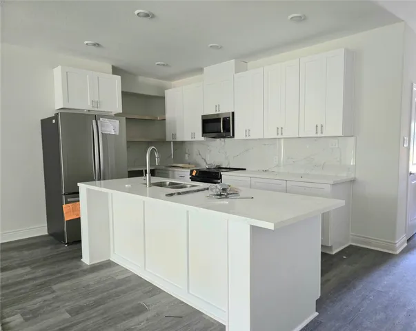 a kitchen with stainless steel appliances white cabinets a sink and a refrigerator