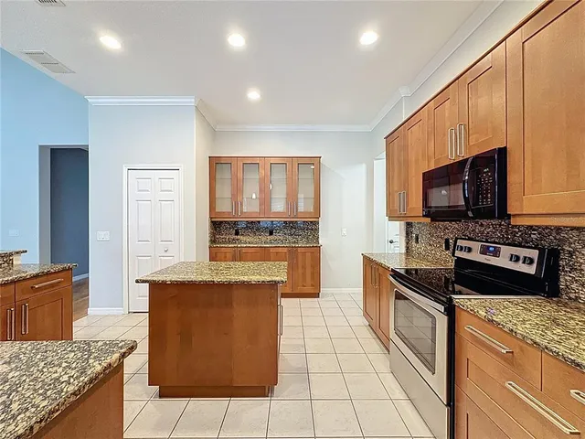 a kitchen with stainless steel appliances granite countertop a refrigerator a stove and a sink