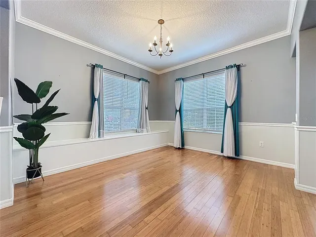 a view of an empty room with wooden floor and a kitchen