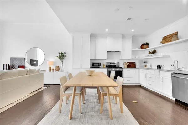 a kitchen with a table chairs a sink dishwasher stove and cabinets with wooden floor