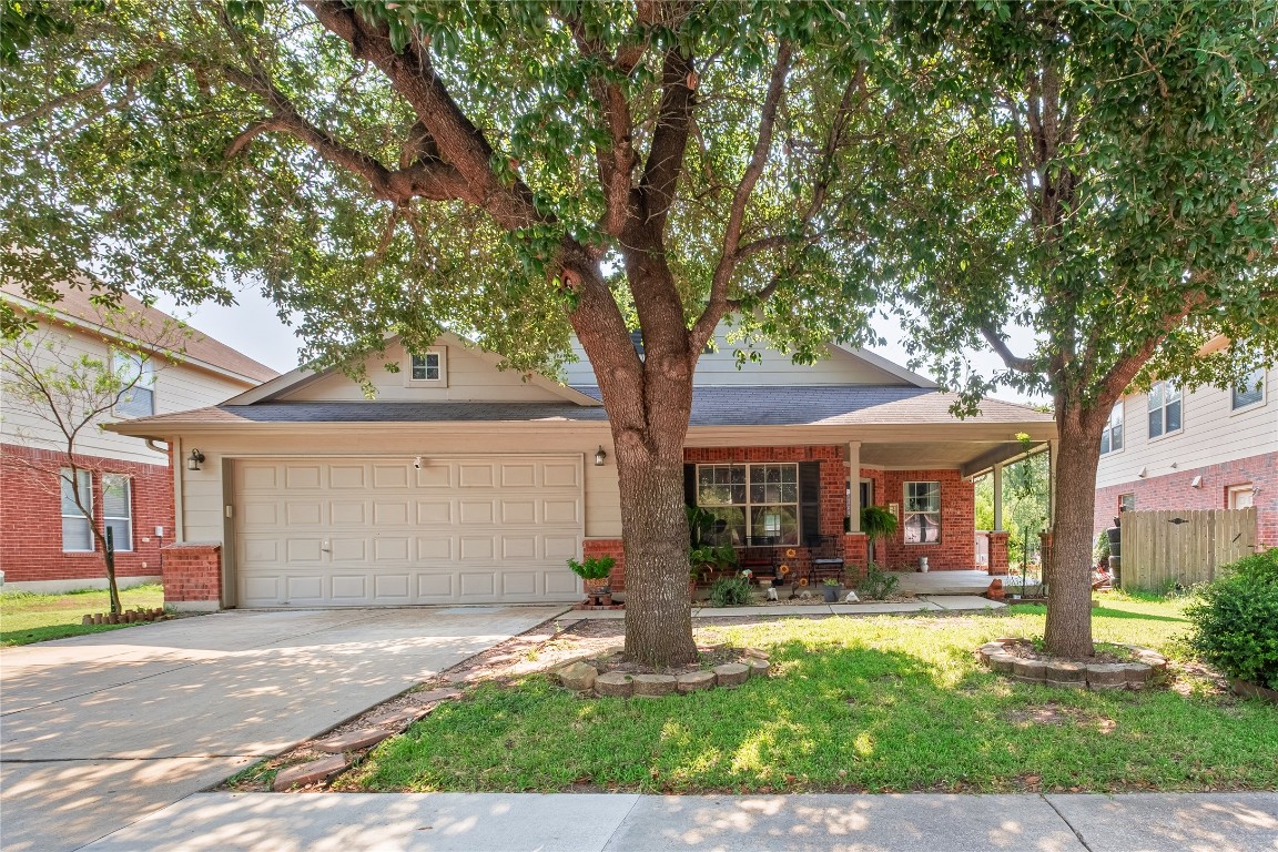 View of front of property featuring covered porch, concrete driveway, brick siding, roof with shingles, and a garage