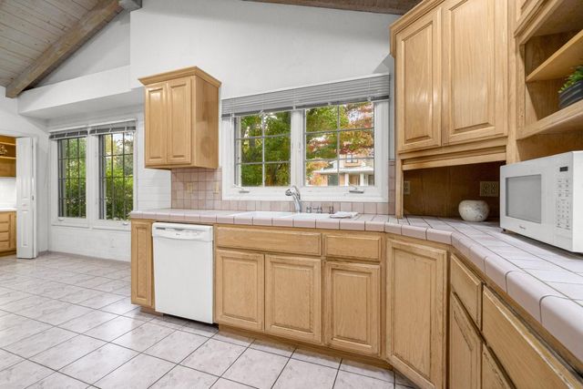 a bathroom with a granite countertop toilet a sink a mirror a window and a bathtub