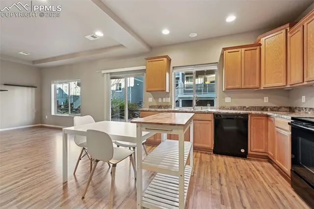 a kitchen with stainless steel appliances granite countertop wooden cabinets a sink a stove a dining table and chairs