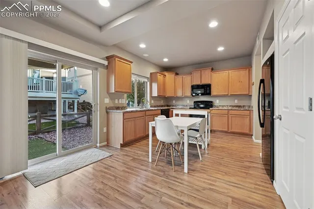 a kitchen with stainless steel appliances granite countertop a stove top oven a sink dishwasher a dining table and chairs with wooden floor