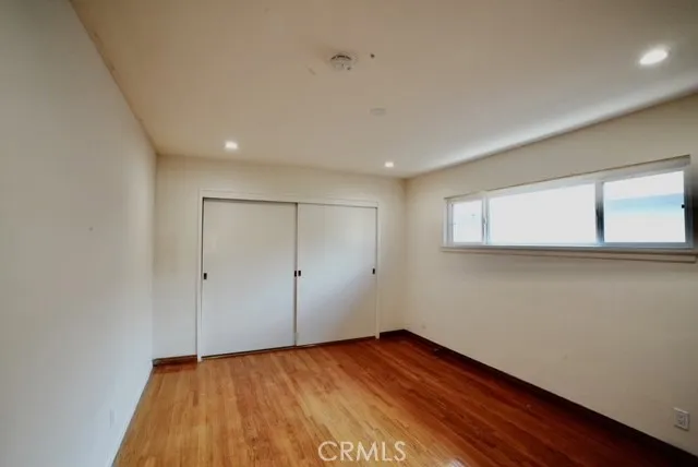 a view of an empty room with wooden floor and closet