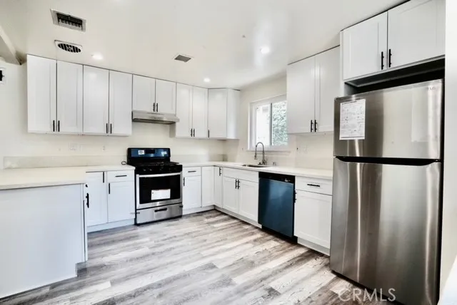 a kitchen with white cabinets stainless steel appliances and a window
