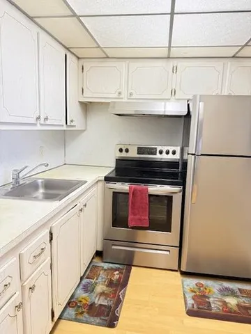 a kitchen with stainless steel appliances granite countertop a refrigerator stove and white cabinets