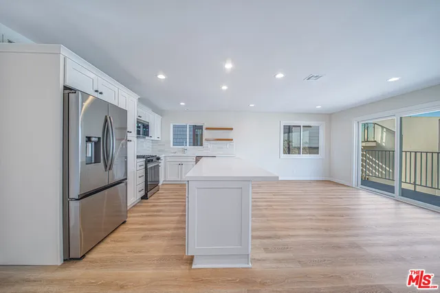 a large kitchen with stainless steel appliances a large counter top and a wooden floors