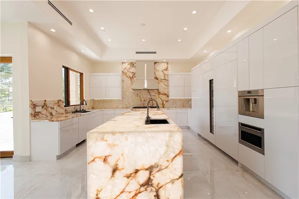 a kitchen with stainless steel appliances kitchen island granite countertop a sink and refrigerator