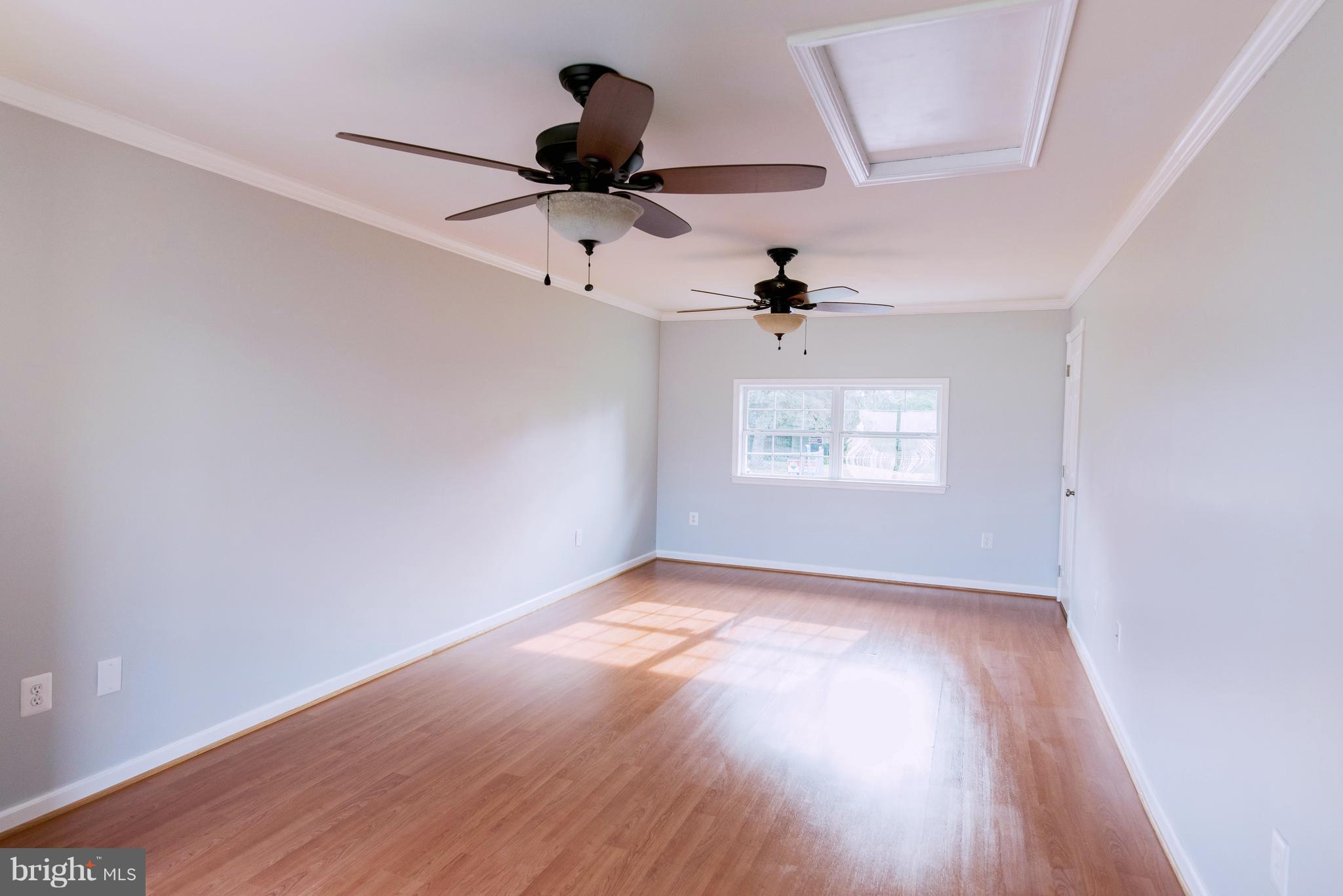 95 Orchard Drive Ranson, WV 25438 - Photo 7 of 22 an empty room with wooden floor ceiling fan and windows