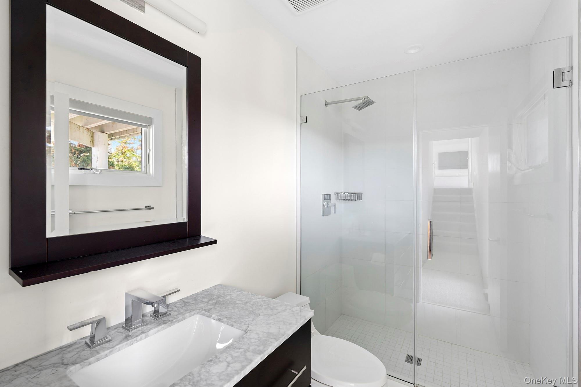 588 Dune Road Westhampton, NY 11978 - Photo 13 of 23 a bathroom with a granite countertop sink toilet a mirror and shower