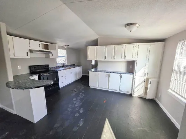 a kitchen with stainless steel appliances a sink a stove a refrigerator cabinets and a window