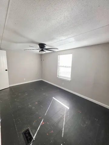 an empty room with windows and ceiling fan