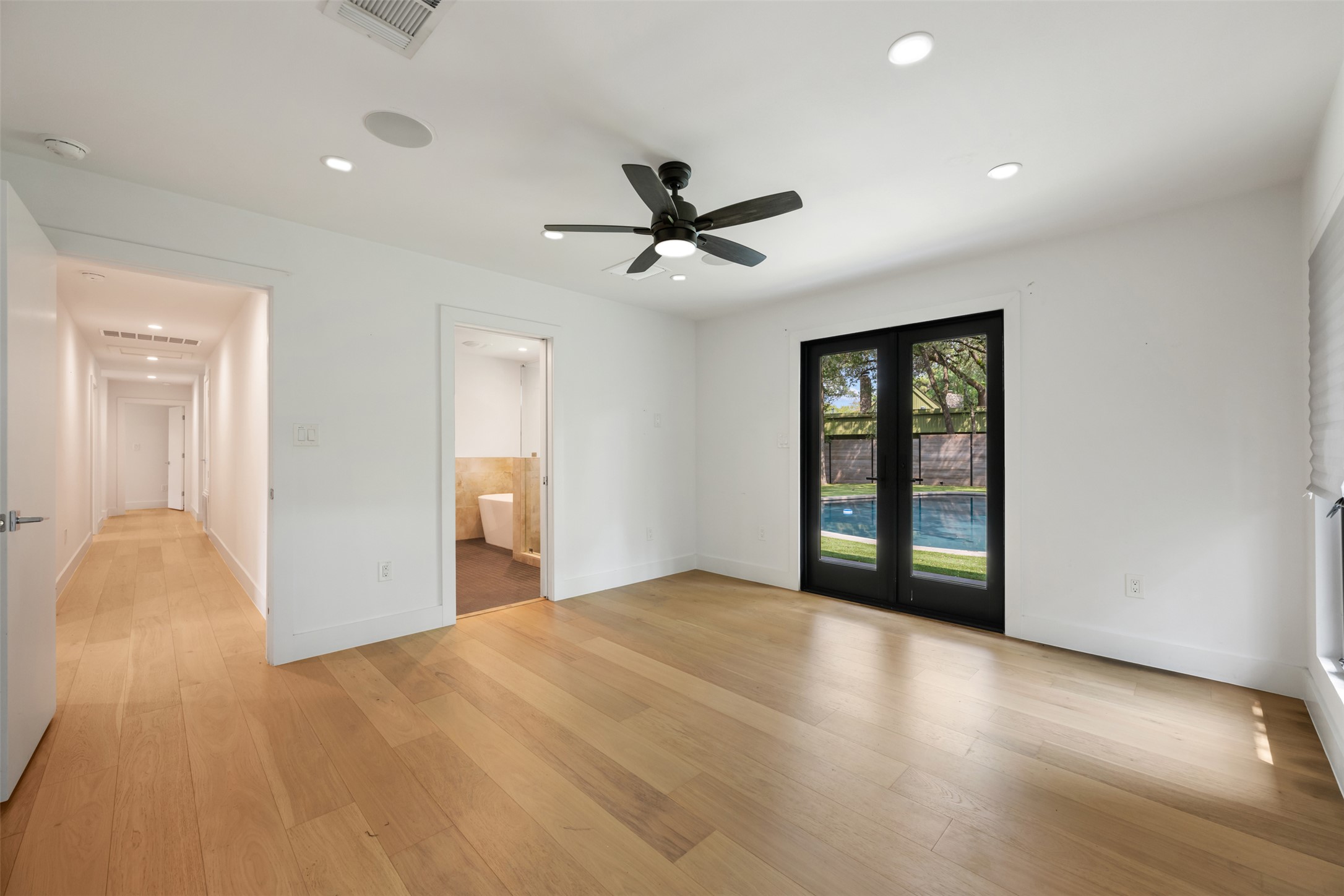 8900 Point W Drive Austin, TX 78759 - Photo 22 of 40 Hardwood floors and a ceiling fan create a comfortable atmosphere in this space, with French doors leading to a private pool.