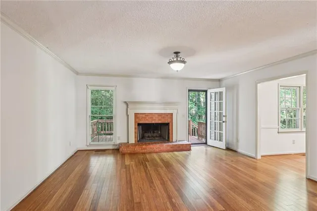 an empty room with windows a fireplace and wooden floor