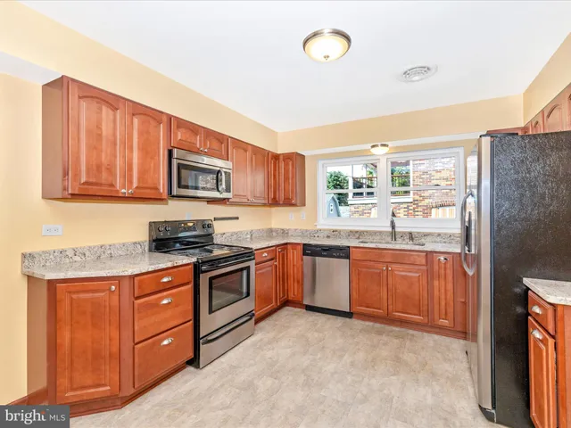 a kitchen with stainless steel appliances granite countertop a stove top oven a sink dishwasher and a refrigerator