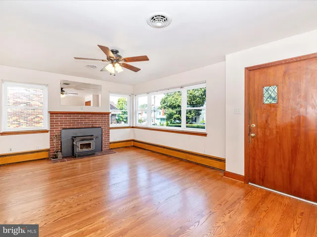 an empty room with windows fireplace and a ceiling fan