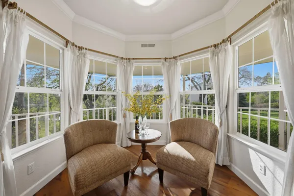 a dining hall with stainless steel appliances lots of white furniture a window and a kitchen view