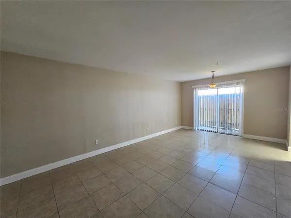 an empty room with chandelier fan and windows