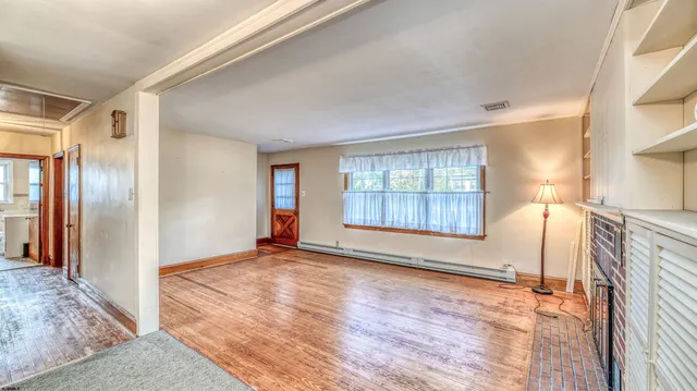 a view of an empty room with wooden floor and a window