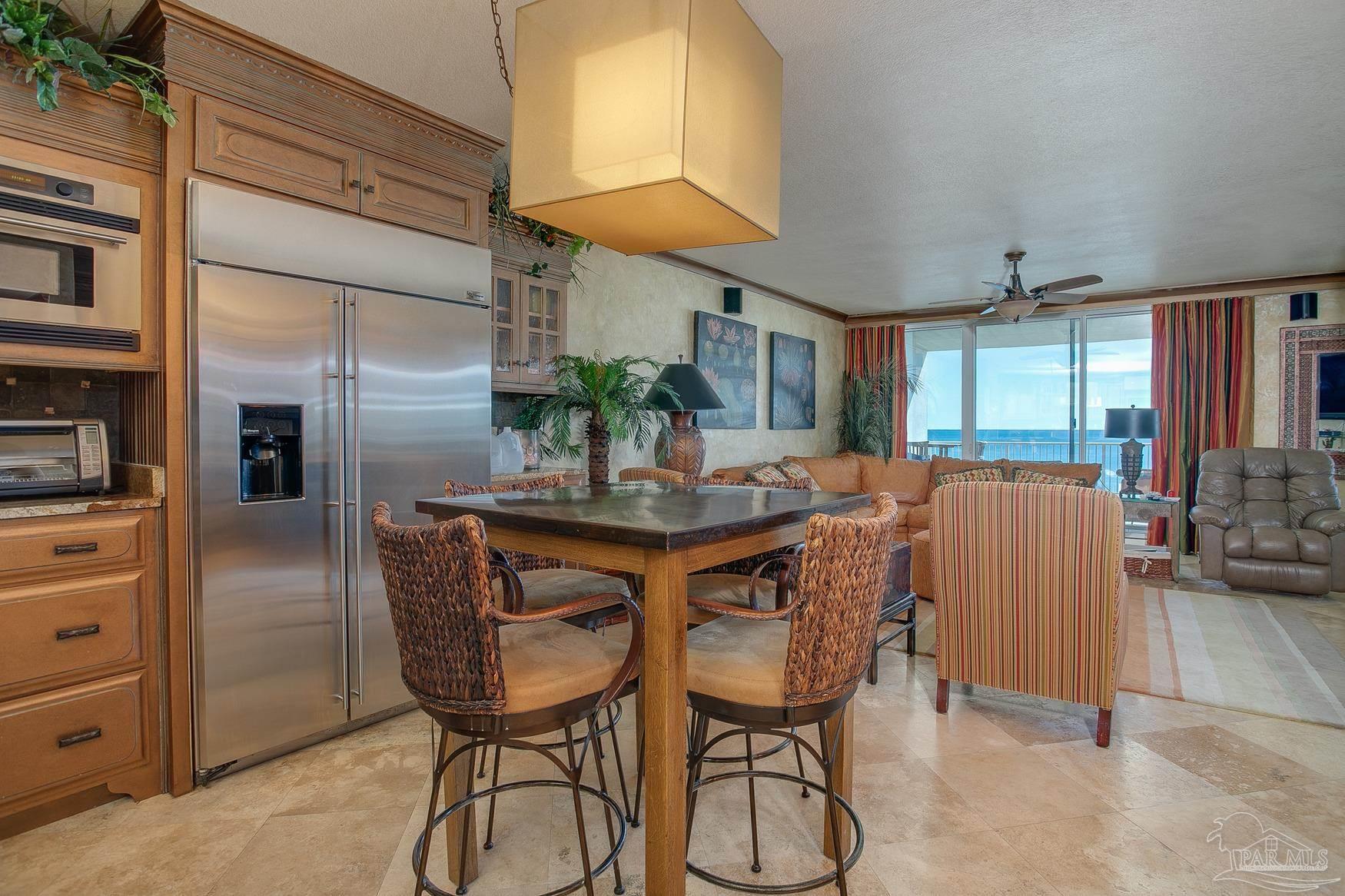16795 Perdido Key Drive, Unit 40304B Perdido Key, FL 32507 - Photo 8 of 42 a kitchen with stainless steel appliances kitchen island granite countertop a table chairs and a refrigerator